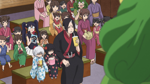 A group of people in traditional Japanese clothing, many of them sporting short horns, sit in rows as if attending a performance of some kind. In the front row is a man in a dark yukata with a horn in the middle of his head, holding a soft drink; and two young girls in kimono, one with popcorn and the other a soft drink. All three look unhappy with whatever they're watching.