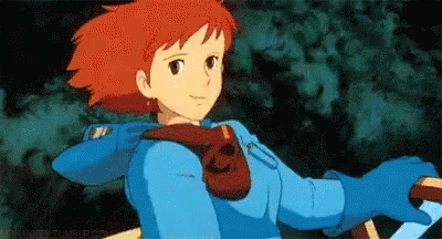 A teen girl (Nausicaa) in a blue flight sight smiles slightly and gives a thumbs-up.