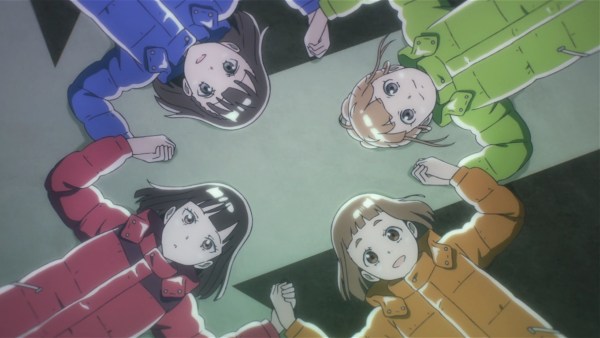 Four teen girls wearing multicolored parks lie on their backs, holding hands and looking up at the sky