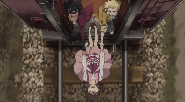 A girl hangs from the back of a train. Two people, a Spanish woman and a blonde boy, grab hold of her hands to keep her from falling.